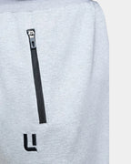 Détail poche zippée et logo brodé du jogging sarouel gris chiné