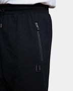 Détail poche zippée et logo brodé du jogging sarouel noir