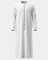 Qamis Dubaï blanc Al Rezam vu de face — col rond, empiècement surpiqué en V et gland tarbousha tressé