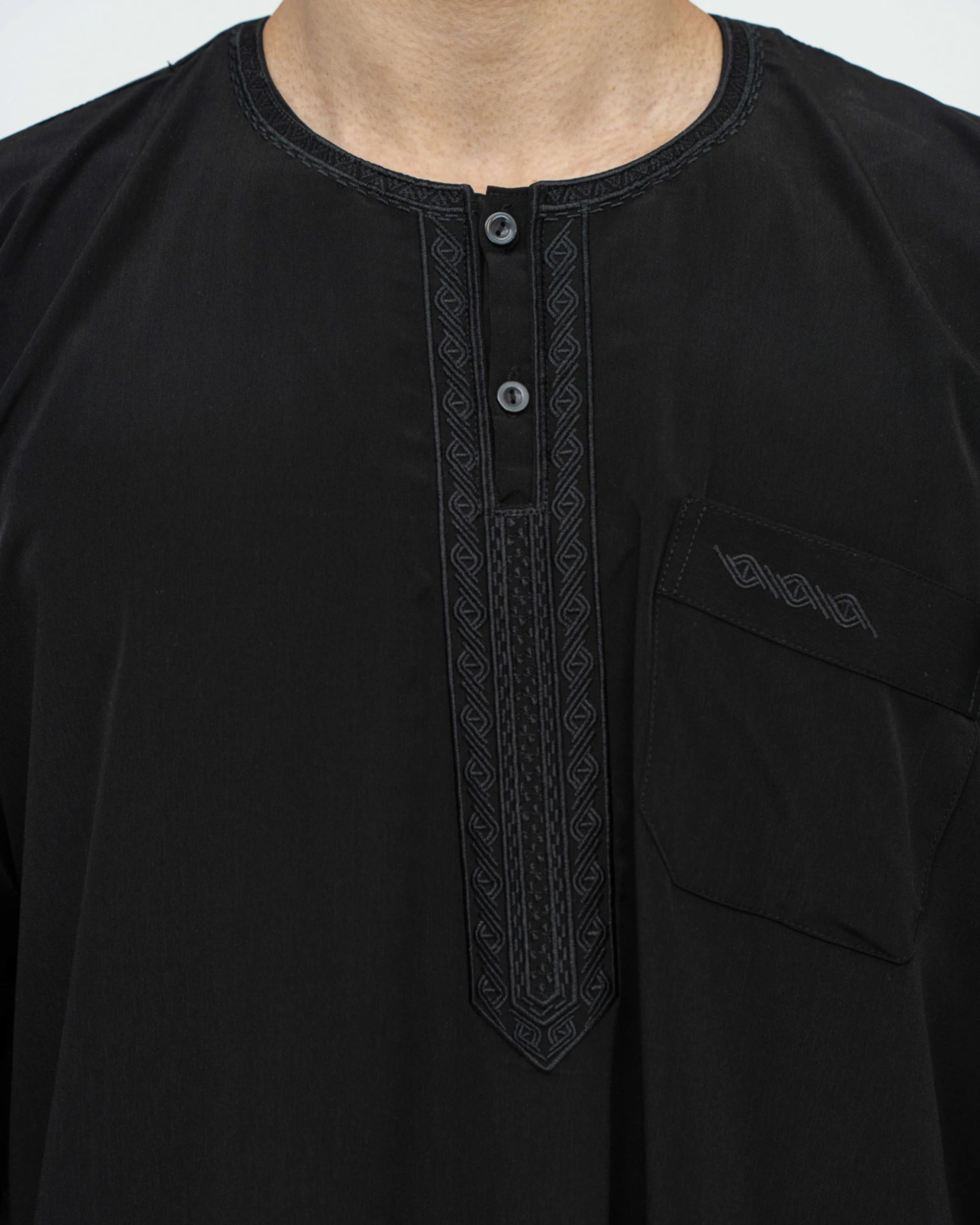 Détail du col rond brodé et du plastron brodé sur le buste du qamis marocain noir Al Rezam