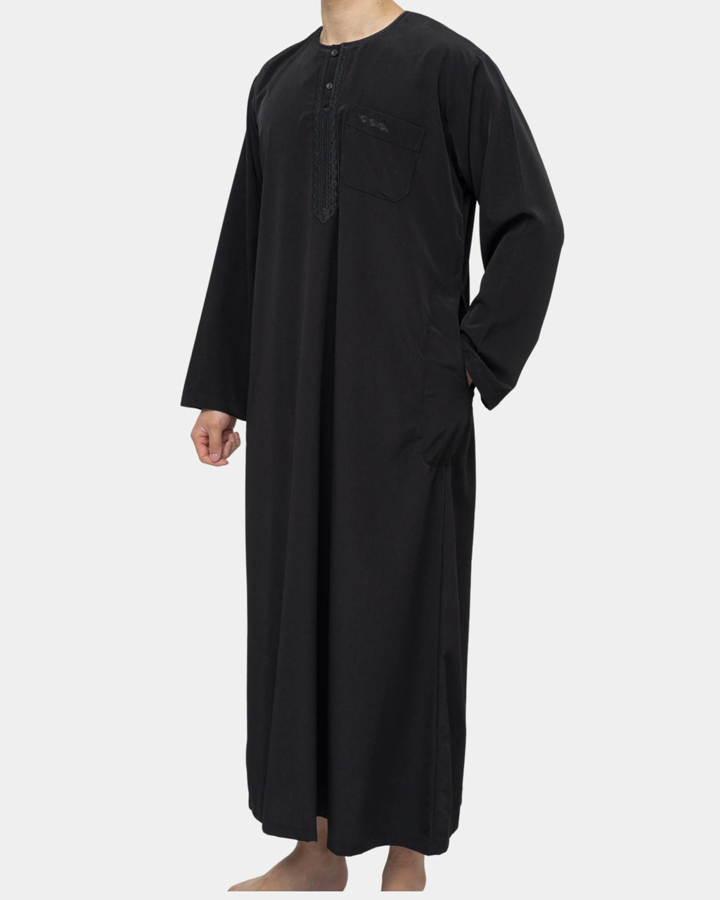 Qamis marocain noir Al Rezam porté de profil — tombé fluide, poches latérales et col rond brodé