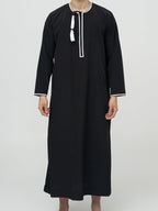 homme musulman portant un qamis omanais noir de face