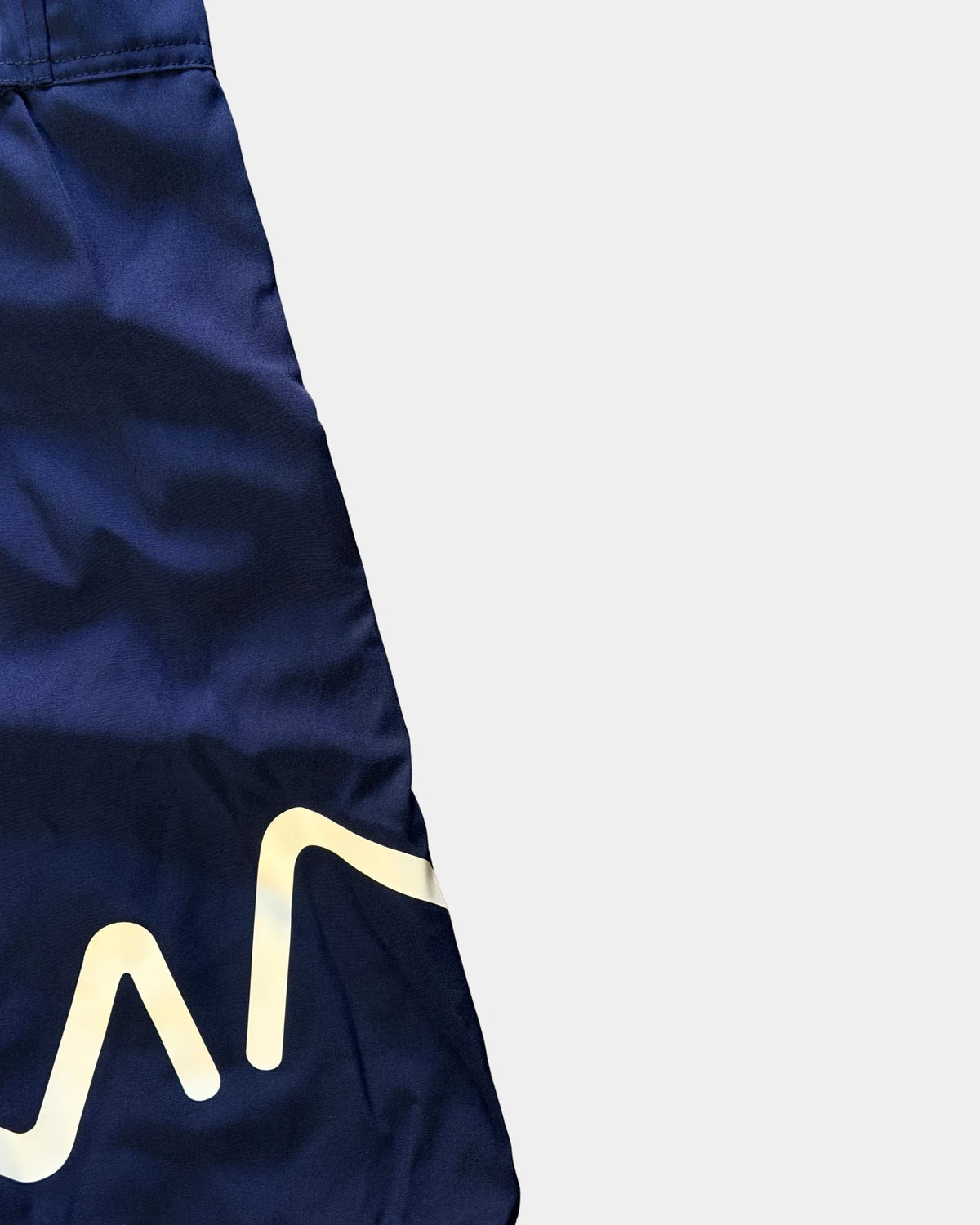 Détail du logo réfléchissant sur la jambe du short de bain awra bleu marine Al Rezam
