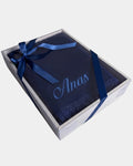 Tapis de prière en velours bleu marine avec le prénom Anas brodé en fil bleu clair, présenté dans un coffret cadeau blanc noué d'un ruban bleu marine assorti