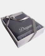 Tapis de prière en velours gris anthracite avec le prénom Dayan brodé en fil argenté, présenté dans un coffret cadeau blanc noué d'un ruban gris assorti