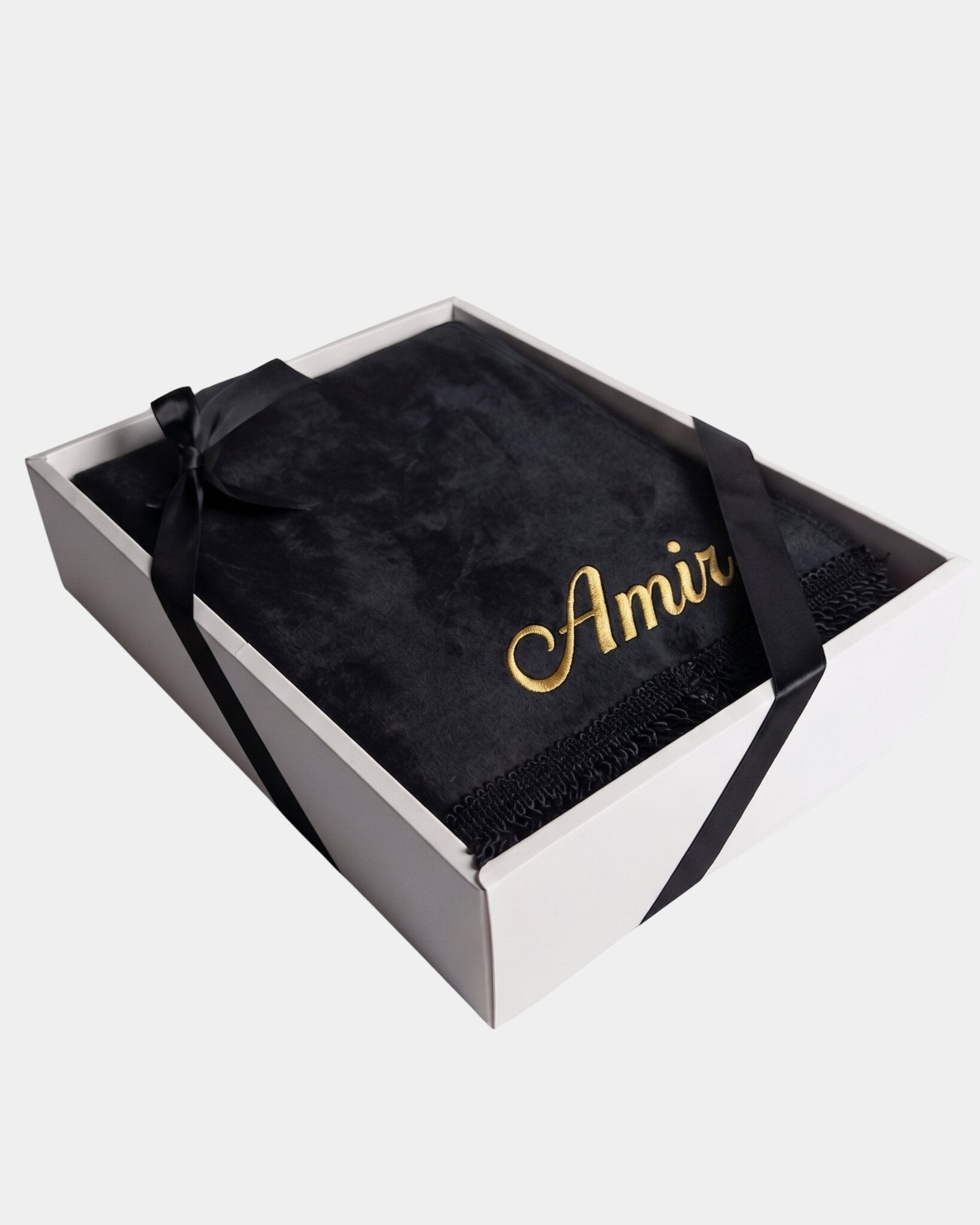 Tapis de prière en velours noir avec le prénom Amir brodé en fil doré, présenté dans un coffret cadeau blanc noué d'un ruban noir assorti