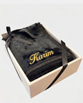 Tapis de prière épais en velours noir à motif embossé avec le prénom Karim brodé en fil doré, présenté dans un coffret cadeau blanc noué d'un ruban noir assorti