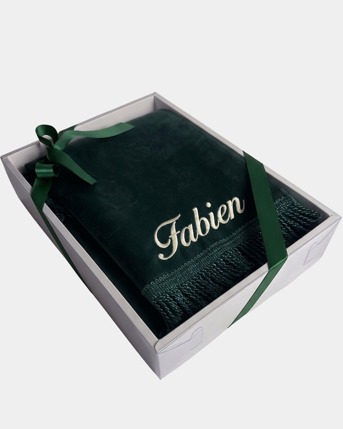 Tapis de prière en velours vert sapin avec le prénom Fabien brodé en fil ivoire, présenté dans un coffret cadeau blanc noué d'un ruban vert assorti